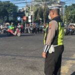 Anggota Polsek Tambaksari berjaga dan mengatur lalu lintas di Perempatan Kedung Cowek, Surabaya